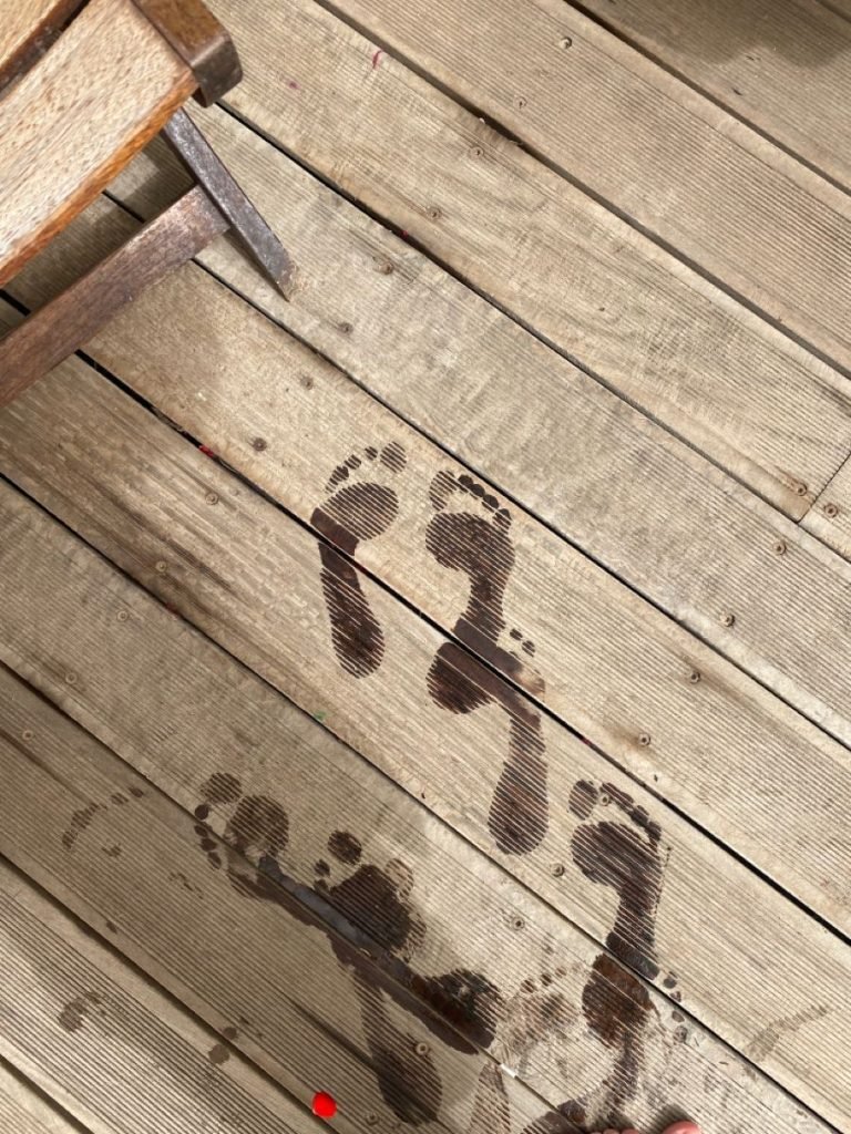 Wet footprints on a wooden deck after a cold plunge